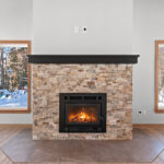 14421 N Paya Lake Rd Three Seasons Fireplace with Stacked Stone Surround to Mantel Height. Tuscany Scabas natural stacked stone panels with Evostone "Dune" hearth tile. Heatilator Pioneer II wood-burning fireplace.