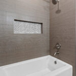 14421 N Paya Lake Rd Alcove Tub with Surround Tiled with Rally "Olive" tile and Akua Mirada "White Mix" mosaic tile in recessed shampoo niche