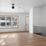 2202 Patty Ln Living Room and Stairs with vertical black iron balusters with LJ smith LJ-4000 maple newel post. Canyon Americas "Fall Branch Hickory" vinyl plank flooring.